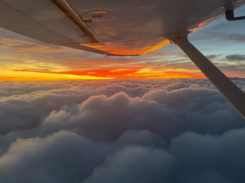 View of a plane's left wing above the clouds