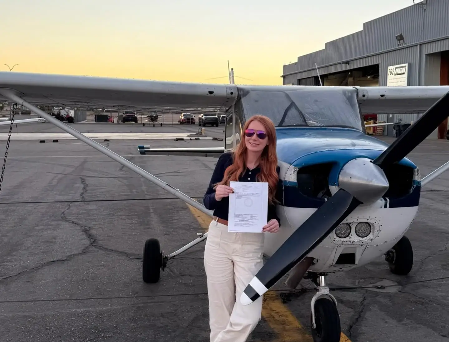 Student holding certificate in front of airplane