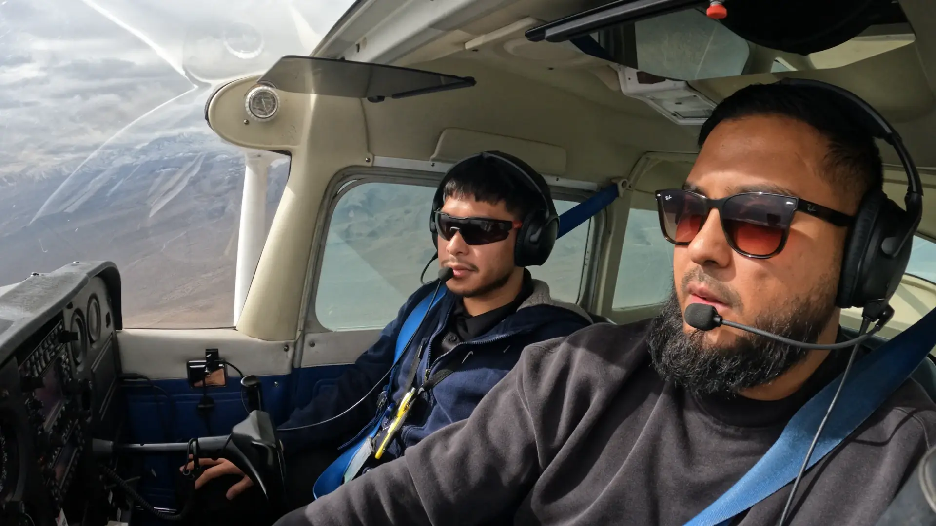 Pilots flying an airplane seen from the front inside the cockpit