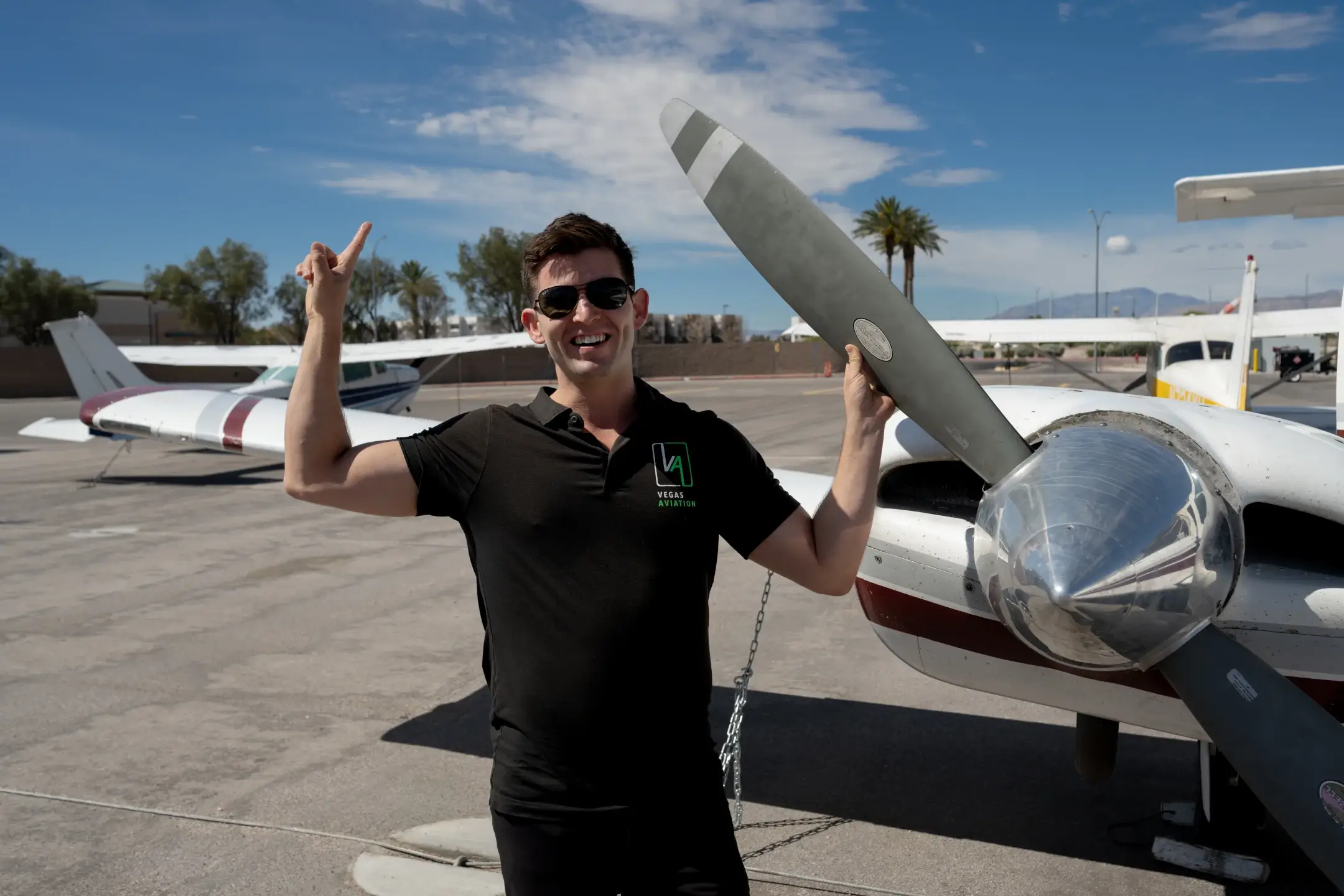 Vegas Aviation employee pointing to the sky while holding onto an airplane's turbine